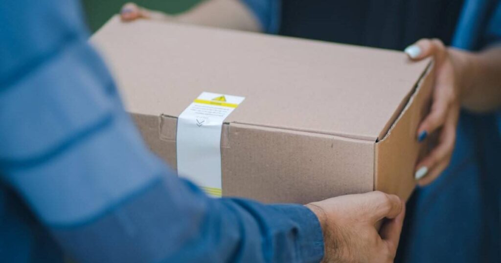 A delivery person handing off a box to a customer. Photo by RoseBox رز باکس on Unsplash.