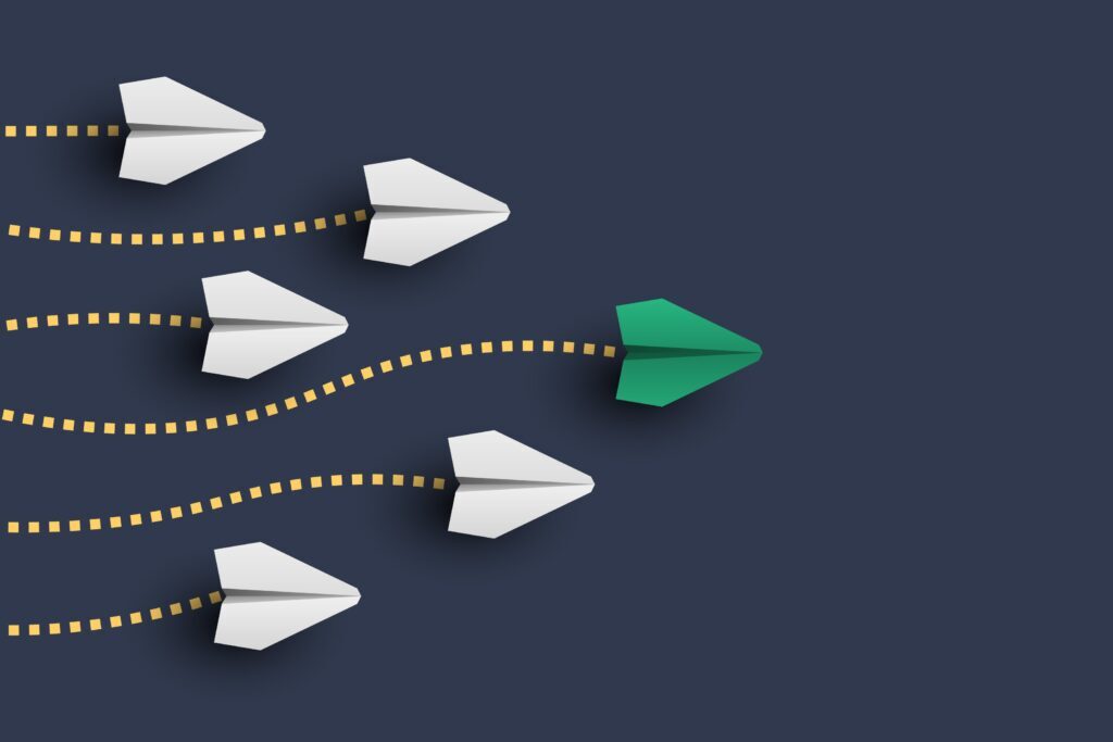 Paper airplanes flying. One green plane is leading the way.