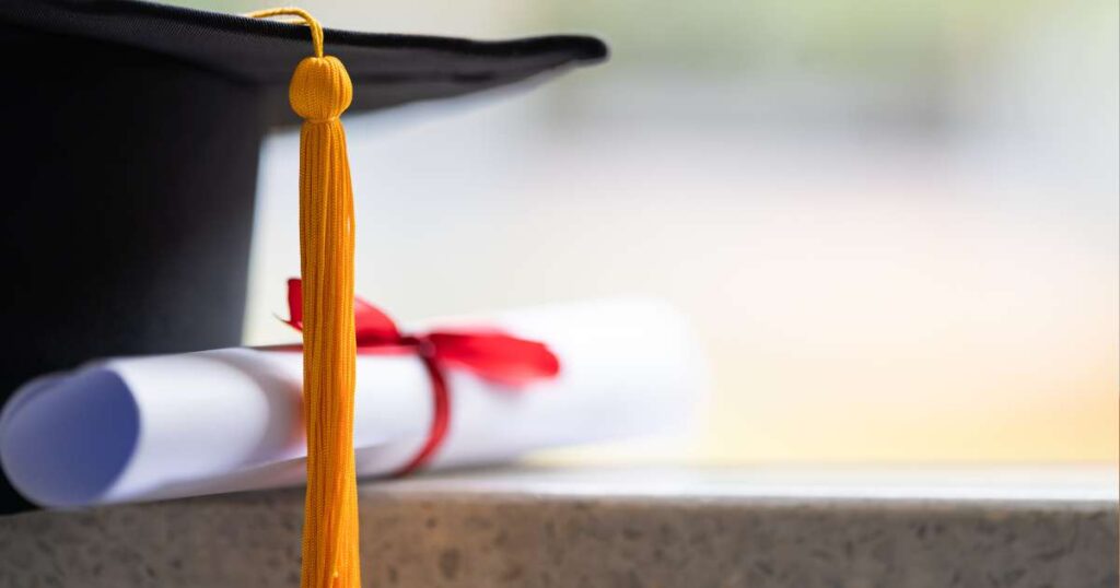 close up of a graduation cap and diploma on a ledge