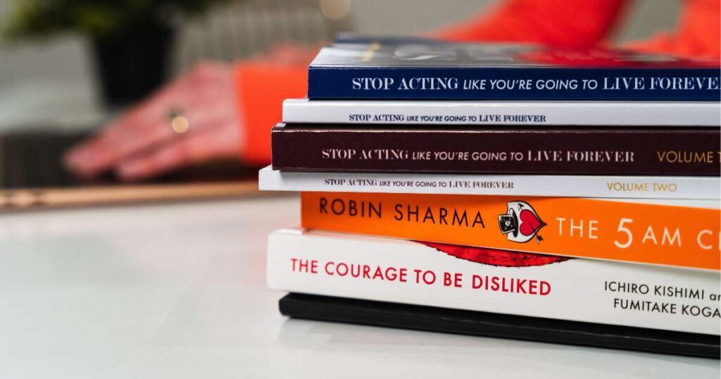 stack of books in front of hands at a laptop keyboard