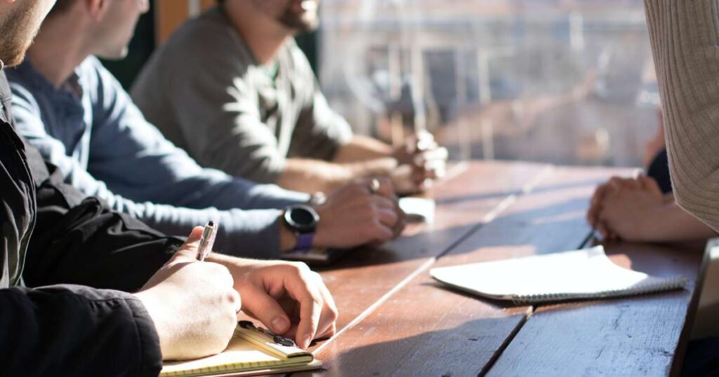 group meeting close up of hands on table taking notes