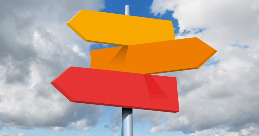 Unlabeled yellow, orange, and red signs on a post pointing in different directions.