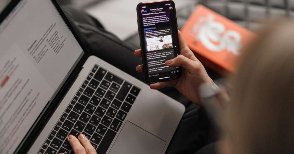 over the shoulder POV of someone checking email on phone and laptop
