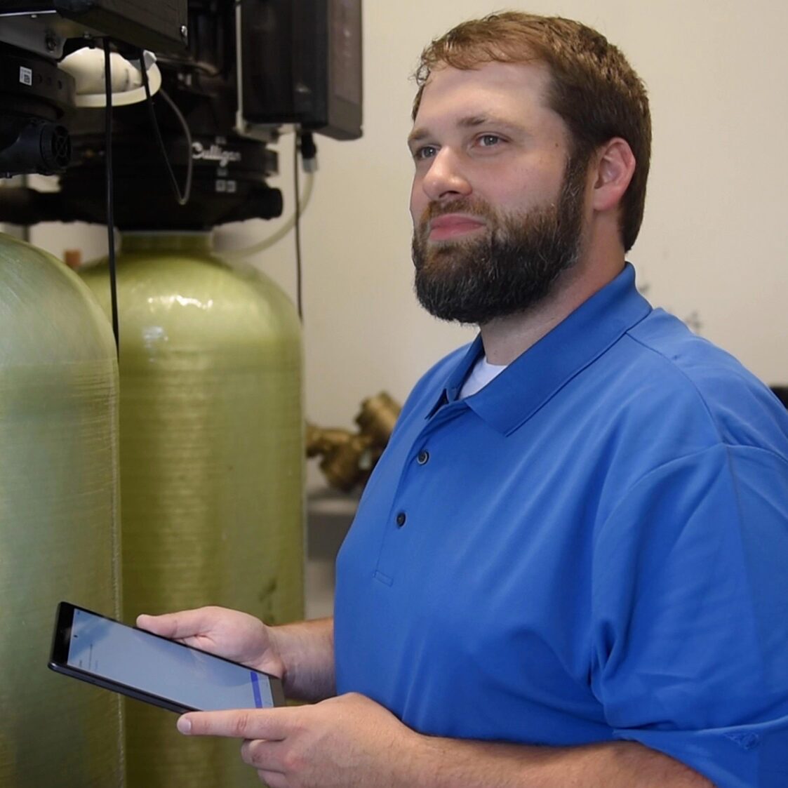 tech on tablet by water softener tanks